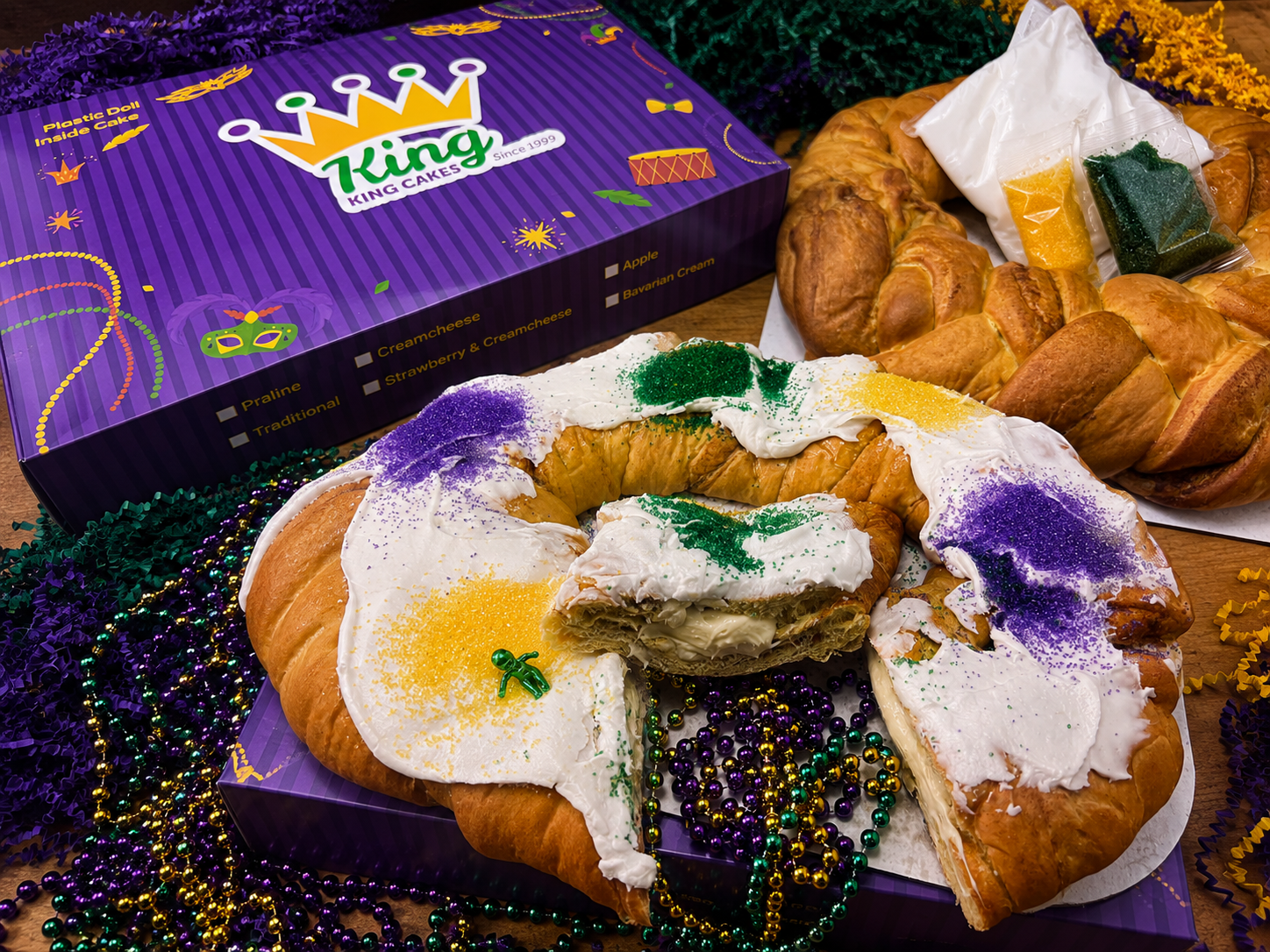 King Cake shipping kit with decorated and un-iced cakes, icing, Mardi Gras sugars, beads, and KingKingCakes packaging