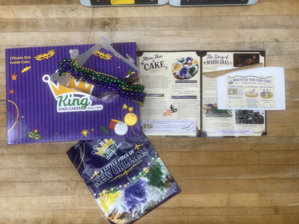 KingKingCakes.com DIY package with icing, sugars, plastic baby, beads, parade doubloons, souvenir knife, paper crown and brochure.