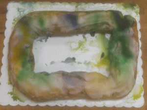 Fully iced king cake after a Ground shipment during 89-degree weather, showing icing movement in transit.