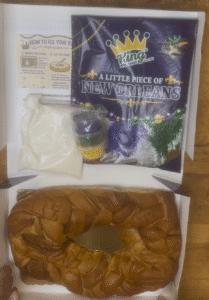 Finished KingKingCakes.com king cake displayed with DIY decorating supplies and Mardi Gras extras.